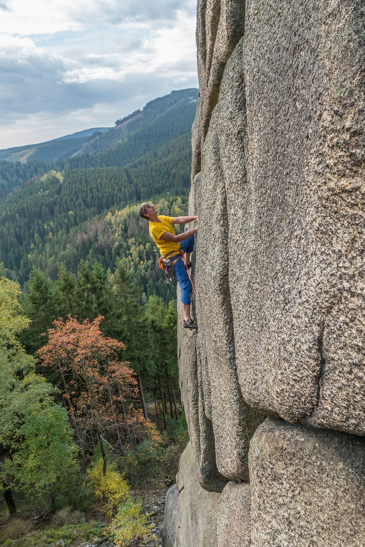 Kletterer an einer Granitwand im Okertal mit Blick über den Wald.